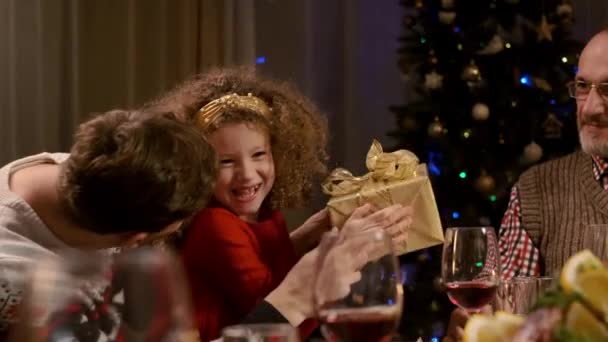 Año Nuevo. La abuela le da un regalo a su nieta. Familia en la mesa de Navidad en apartamento. — Vídeo de stock