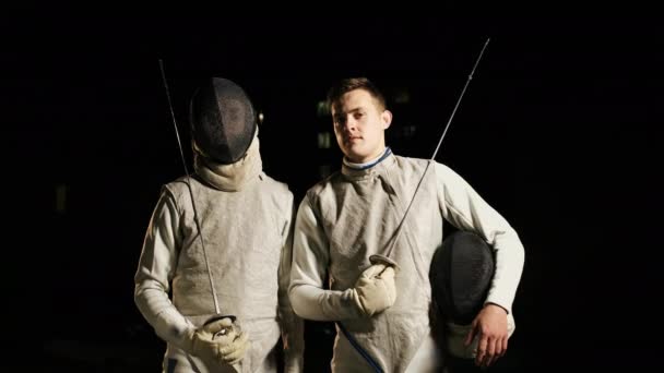 Två Fencers i kostym står bredvid varandra i mörkret. — Stockvideo