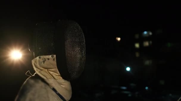 Dois esgrimistas em fatos de esgrima e capacetes esgrima no escuro fora. — Vídeo de Stock