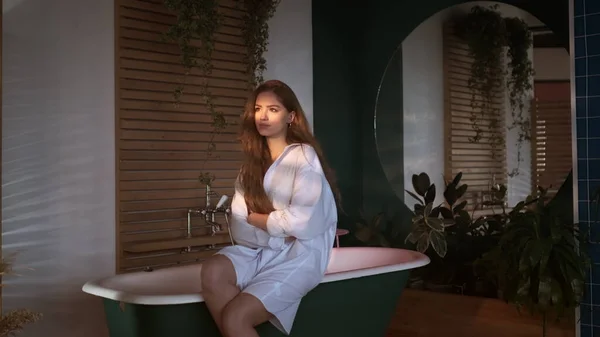 Kaunis punatukkainen tyttö pitkät hiukset valkoinen Miesten paita istuu kylpyammeessa kylpyhuoneessa. — kuvapankkivalokuva