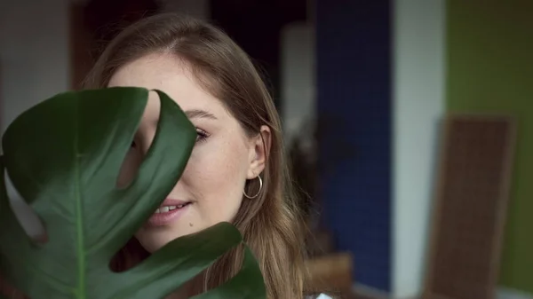 Mädchen Gesicht Blick durch das Blatt der Pflanze. — Stockfoto