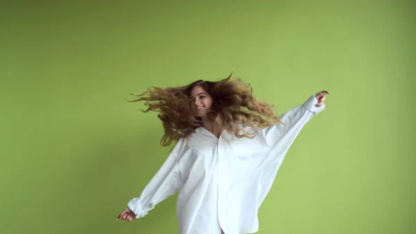 Jenta med langt hår danser på bakgrunn av lys grønn vegg. – stockfoto