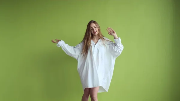 Tyttö pitkät hiukset tanssia taustalla vaalean vihreä seinä. — kuvapankkivalokuva