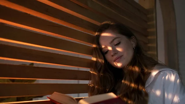 Pen jente med langt hår leser bok. – stockfoto