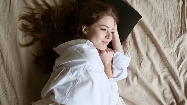 Nuori tyttö herää nukkumisen jälkeen sängyssä. — kuvapankkivalokuva