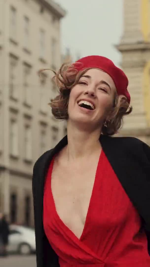 Mujer joven sonriente en rojo camina por la calle de la ciudad. — Vídeo de stock