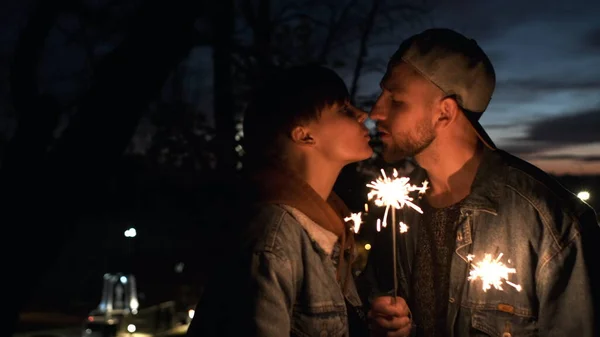 Pareja joven con chispas al aire libre por la noche besos. —  Fotos de Stock