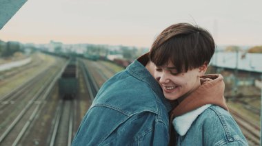 Sevgili ve kız arkadaş köprüde buluşacağız. Kısa saçlı şık bir kız ve şapkalı bir adam..