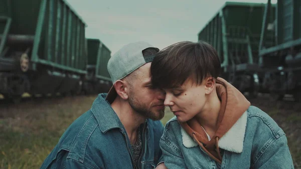 Urban Love Story. Stilvolles Mädchen mit kurzem Haarschnitt und Guy In Cap. Viele Züge um sie herum. — Stockfoto