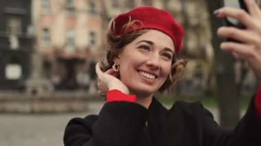 Elinde cep telefonuyla caddenin ortasında dikilen Kırmızılı Şık Genç Kadın.