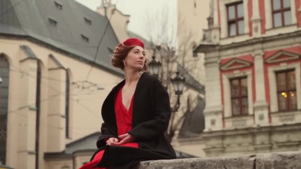 Молодая женщина сидит на улице древнего города и смотрит куда-то. — стоковое видео