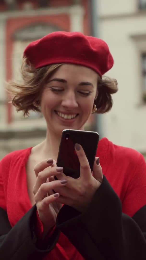 Jovem elegante em pé vermelho no meio da rua com telefone celular em suas mãos. Moldura de vídeo vertical. — Vídeo de Stock