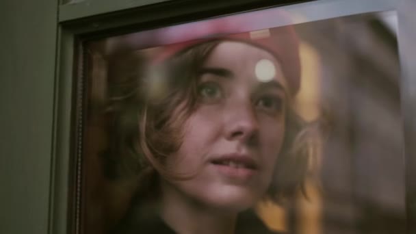 Ung romantisk pige kigger gennem vinduet glas. – Stock-video