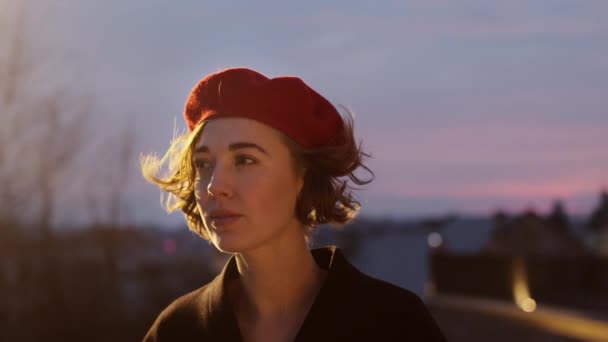 Dämmerung. Porträt einer stilvollen jungen Frau in roter Baskenmütze. Hübsche Frau auf der Straße. — Stockvideo