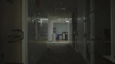 A softly illuminated corridor within an office environment, displaying a range of various office equipment