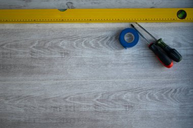 Sarı seviye, iki tornavida ve mavi koli bandı. Evi yenilemek için gerekli şeyler..