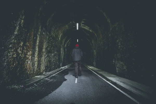 senior man walking into illuminated pedestrian cycle tunnel