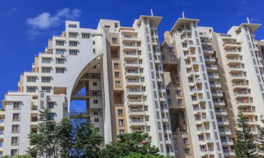 Bangalore, Karnataka, Hindistan - 12 Aralık 2015: Güneşli bir günde mavi gökyüzüne karşı Bangalore banliyösünde yüksek katlı modern bir apartman kompleksi.