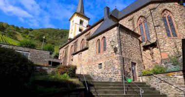 Almanya 'daki Moselle nehri boyunca Bremm köyünde mavi gökyüzüne karşı St Laurentius kilisesi. Sonbaharda.