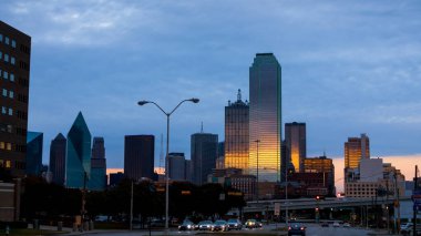 Dallas şehir merkezinin panoramik manzarası alacakaranlık altında gökyüzü ve binaya yansıyan ışık.