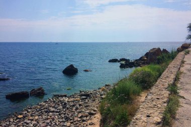 Çakıl taşları, mavi su ve yeşil çim ile Odessa sahil. Sıcak yaz havası. İnsanlar olmadan