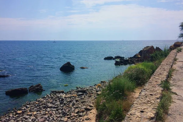Çakıl taşları, mavi su ve yeşil çim ile Odessa sahil. Sıcak yaz havası. İnsanlar olmadan