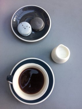 Hafif bir masa arka plan üzerinde mavi bir tabak üzerinde kahve ve macaroons