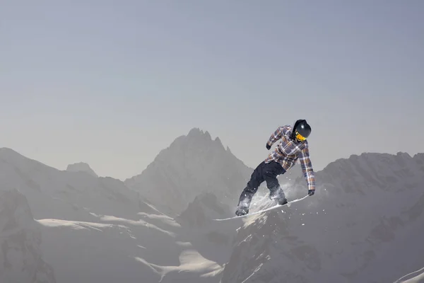Repülő snowboardos a hegyekben. Extrém téli sport. — Stock Fotó
