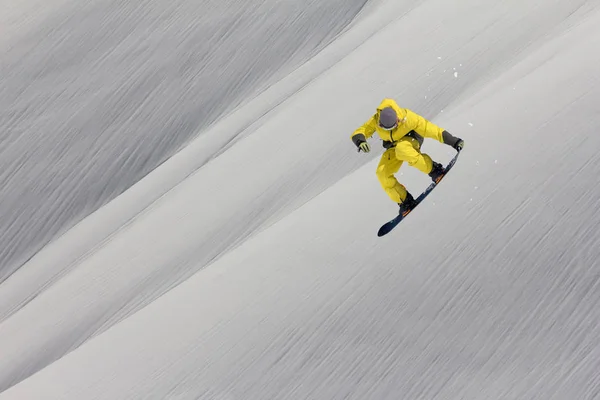 Um snowboarder voador nas montanhas. Extremo esporte de inverno. — Fotografia de Stock