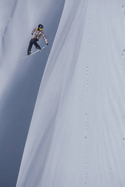 Um snowboarder voador nas montanhas. Extremo esporte de inverno. — Fotografia de Stock