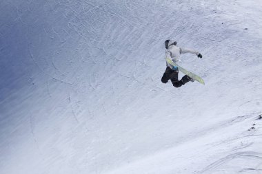 Karlı yamaçta uçan snowboardcu. Kış sporları, snowboard sporları.