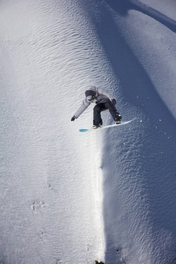 Karlı yamaçta uçan snowboardcu. Kış sporları, snowboard sporları.
