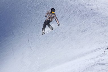 Karlı yamaçta uçan snowboardcu. Kış sporları, snowboard sporları.