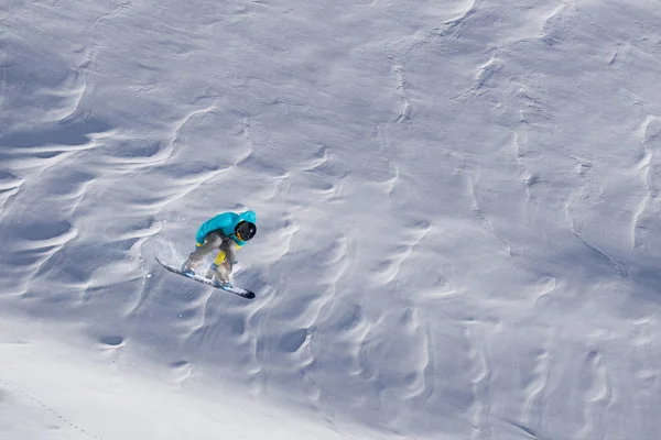 Snowboardzista lecący na tle śnieżnego stoku. Sporty ekstremalne zimowe, snowboarding. — Zdjęcie stockowe