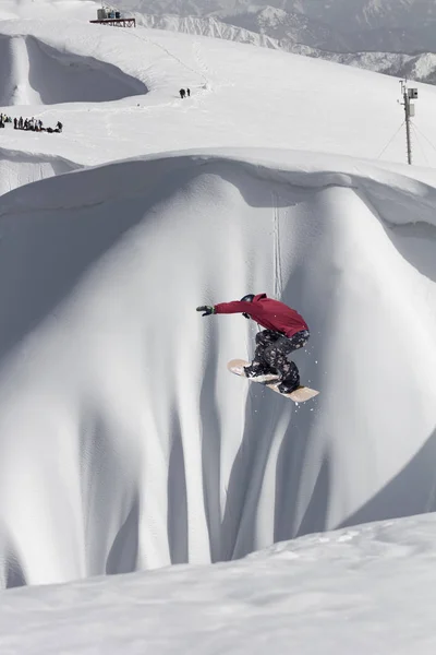 Snowboardzista lecący na tle śnieżnego stoku. Sporty ekstremalne zimowe, snowboarding. — Zdjęcie stockowe