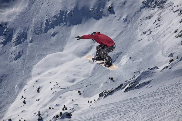 Snowboarder volando en el fondo de la pendiente nevada. Deportes extremos de invierno, snowboard. — Foto de Stock