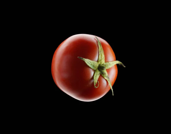 Rote Tomate auf dunklem Hintergrund, isoliert auf schwarzem Hintergrund. — Stockfoto