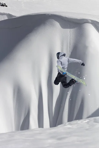 Snowboarder volando en el fondo de la pendiente nevada. Deportes extremos de invierno, snowboard. — Foto de Stock