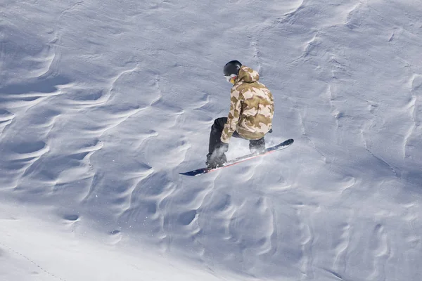 Snowboarder volando en el fondo de la pendiente nevada. Deportes extremos de invierno, snowboard. —  Fotos de Stock