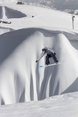 Karlı yamaçta uçan snowboardcu. Aşırı kış sporları, snowboard sporları. Boşluğu kopyala.