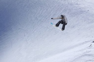 Karlı yamaçta uçan snowboardcu. Kış sporları, snowboard sporları.