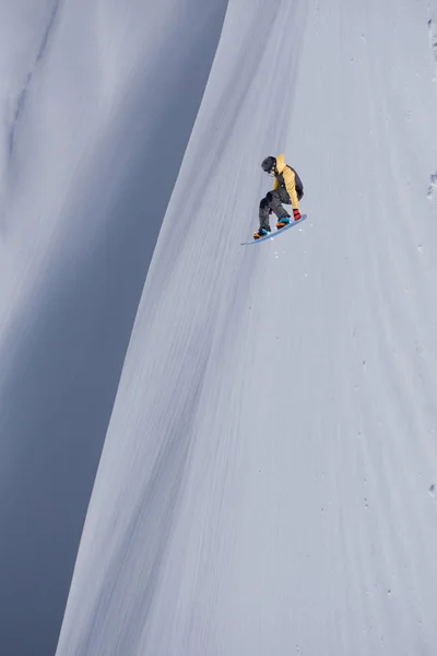 Snowboardzista lecący na tle śnieżnego stoku. Sporty ekstremalne zimowe, snowboarding. — Zdjęcie stockowe