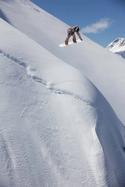 Snowboarder volando en el fondo de la pendiente nevada. Deportes extremos de invierno, snowboard. — Foto de Stock