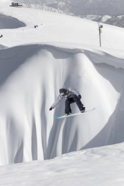 Karlı yamaçta uçan snowboardcu. Kış sporları, snowboard sporları.