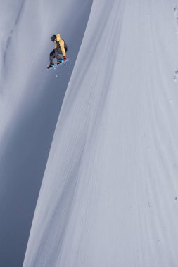 Karlı yamaçta uçan snowboardcu. Kış sporları, snowboard sporları.