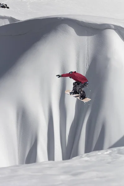 Snowboarder volando en el fondo de la pendiente nevada. Deportes extremos de invierno, snowboard. — Foto de Stock