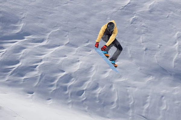 Snowboardos repül a háttérben a havas lejtőn. Extrém téli sportok, snowboardozás. — Stock Fotó