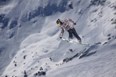 Karlı yamaçta uçan snowboardcu. Kış sporları, snowboard sporları.