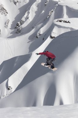 Karlı yamaçta uçan snowboardcu. Kış sporları, snowboard sporları.