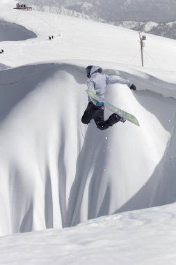 Karlı yamaçta uçan snowboardcu. Kış sporları, snowboard sporları.
